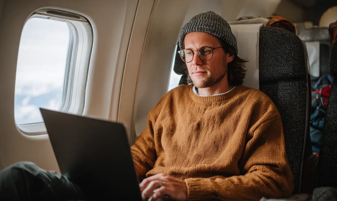 Digital nomad working on a laptop on an airplane