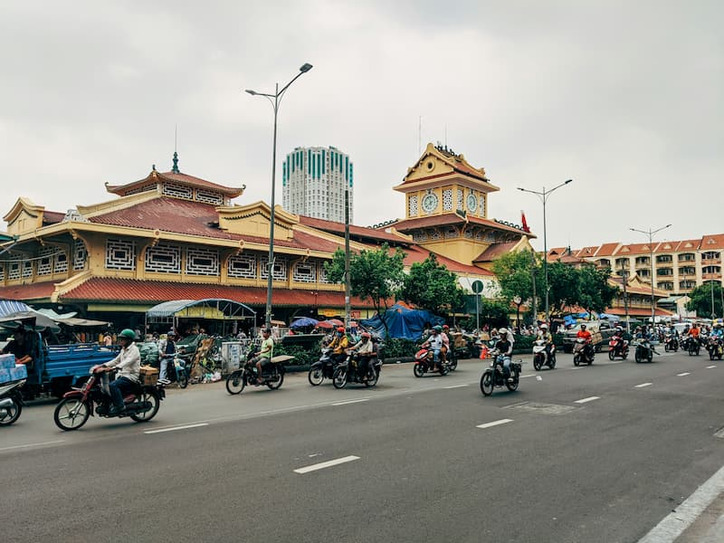 A bustling street in Ho Chi Minh City, Vietnam, with motorbikes and traditional architecture.