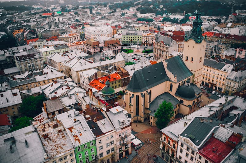 Aerial view of Lviv, Ukraine's Old Town, with diverse rooftops, church spires, and a market square.