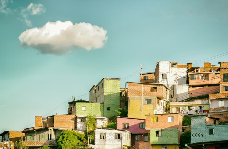 Colorful houses built on a hillside under a bright blue sky with a single white cloud.