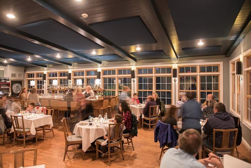 A busy dining room at Mezze Bistro + Bar with many tables and a long bar.