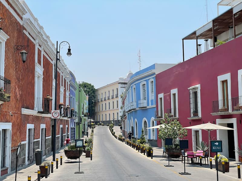 A colorful street scene in Puebla, Mexico, with traditional tiled buildings and flowers.