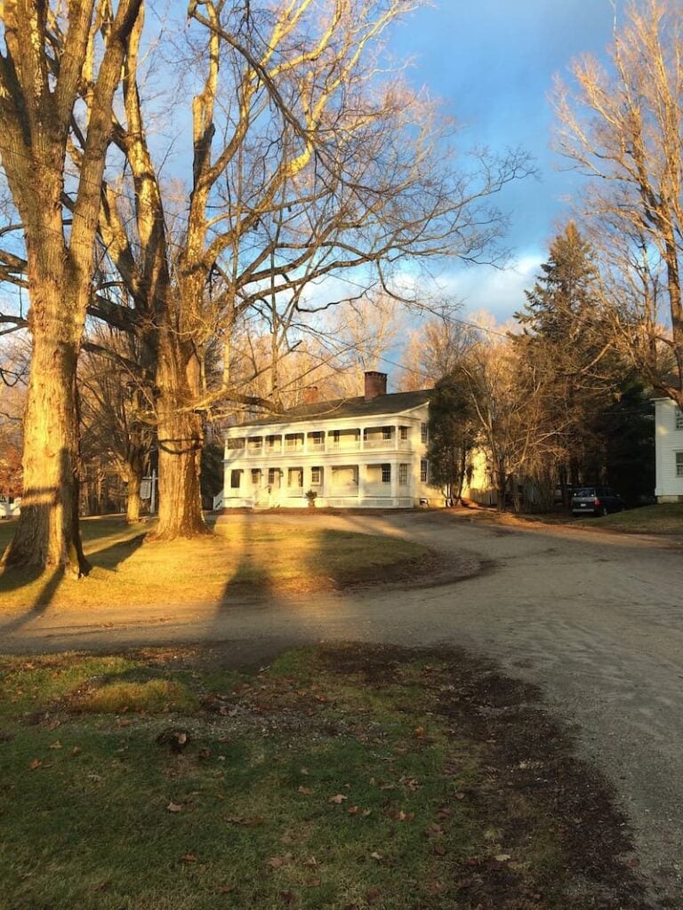 The Old Inn on the Green, a white historic building surrounded by large bare trees.