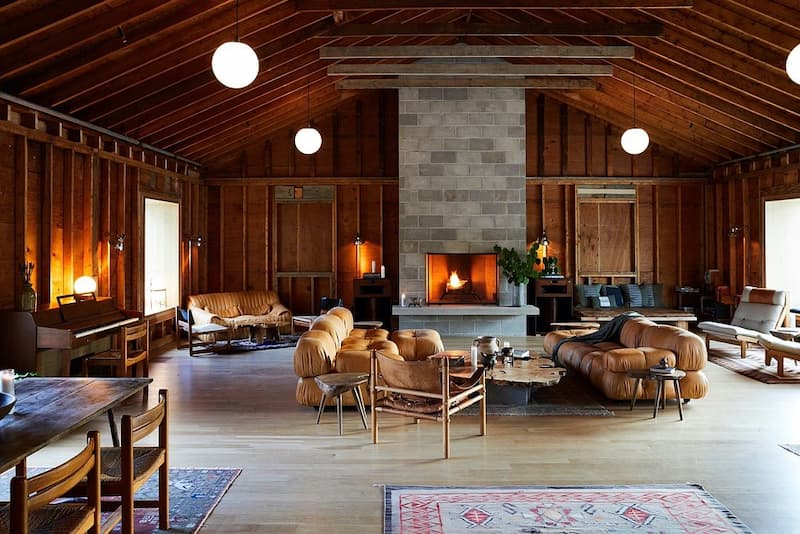 A spacious common area at Tourists with a large fireplace, leather sofas, and wood walls.