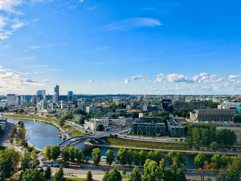 Aerial view of Vilnius, Lithuania, with a meandering river and modern city buildings.