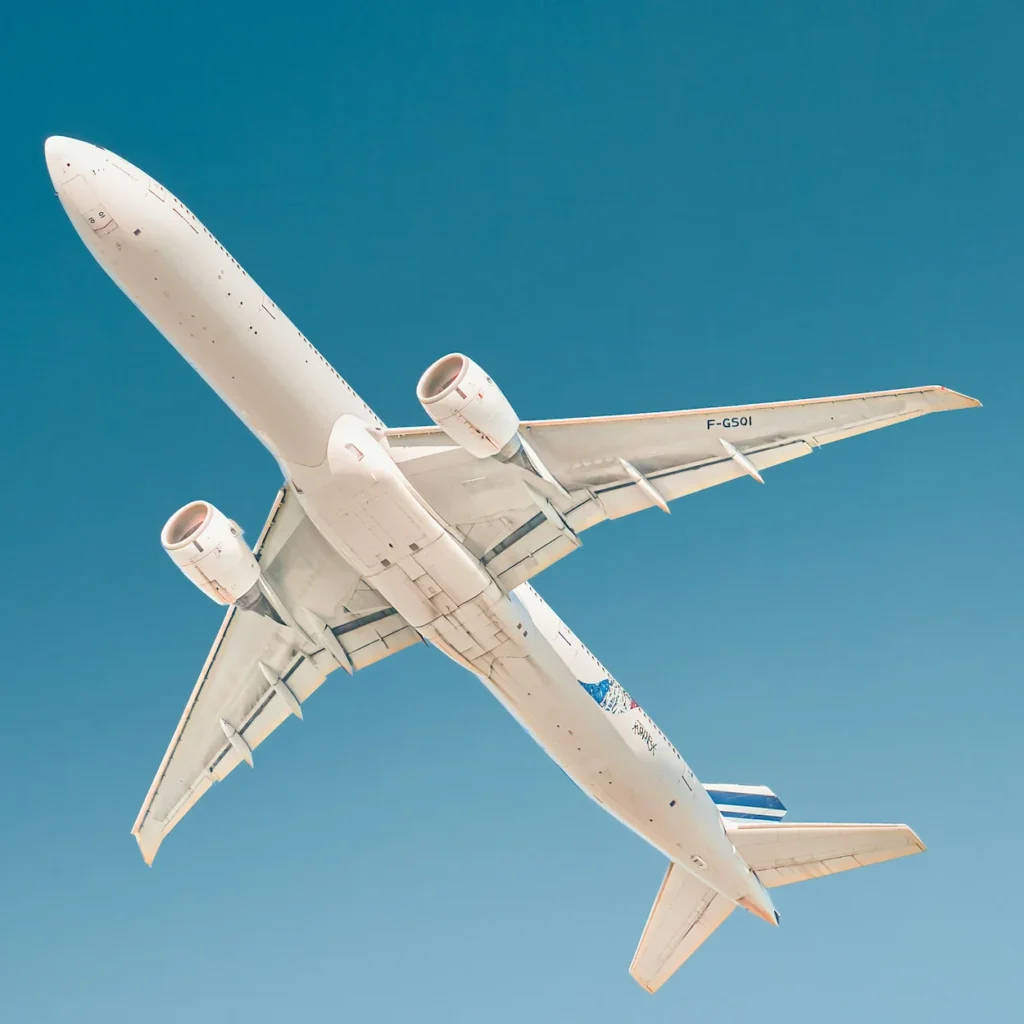 Underside view of an Air France Boeing 777 airplane flying in a clear blue sky with its landing gear fully retracted
