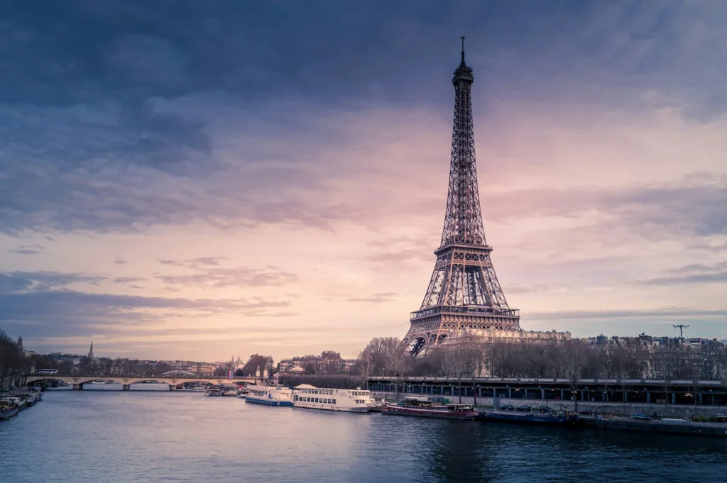 The Eiffel Tower standing beside the Seine River at sunset in Paris