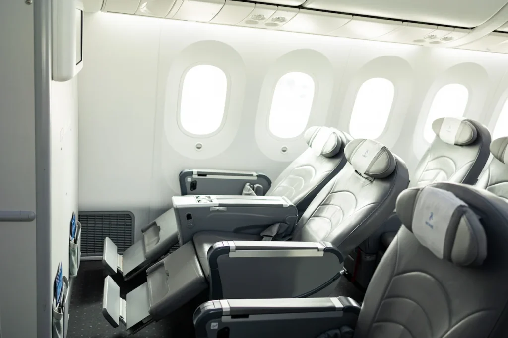 Spacious grey leather premium airplane seats with extendable leg rests next to large windows
