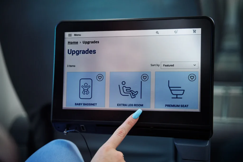A passenger's finger points to the "Extra Leg Room" option on an inflight entertainment screen