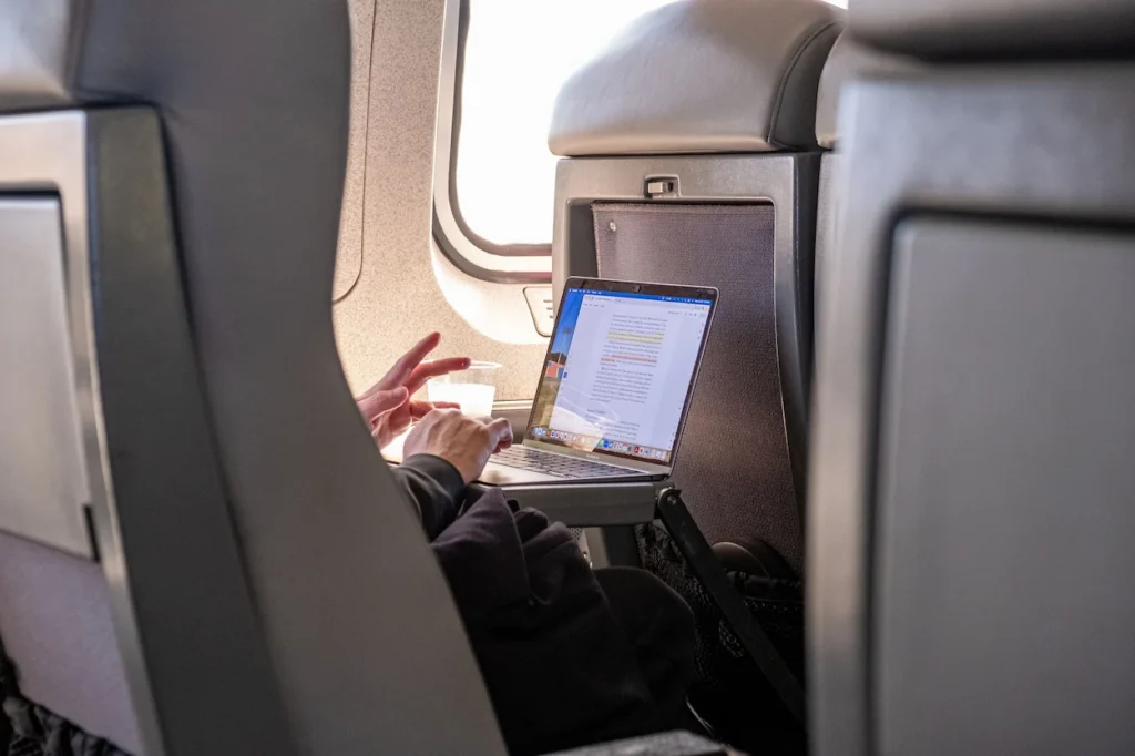 A passenger using a laptop on an airplane tray table during a flight