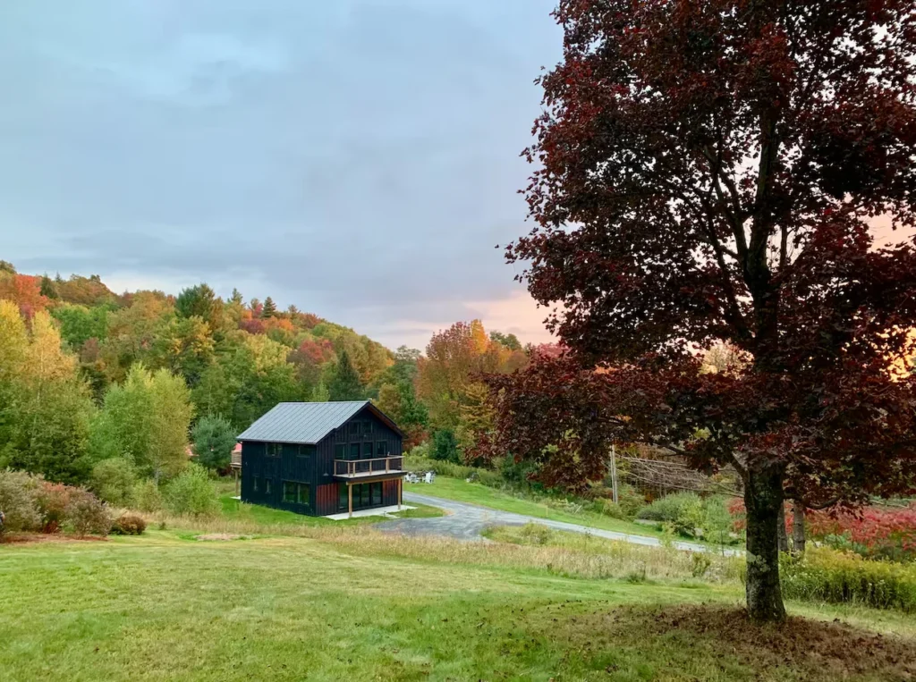 Black modern retreat in Waitsfield, Vermont, surrounded by autumn trees