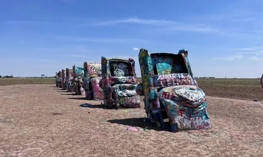 A row of graffiti-covered cars is half-buried in the ground at Cadillac Ranch.