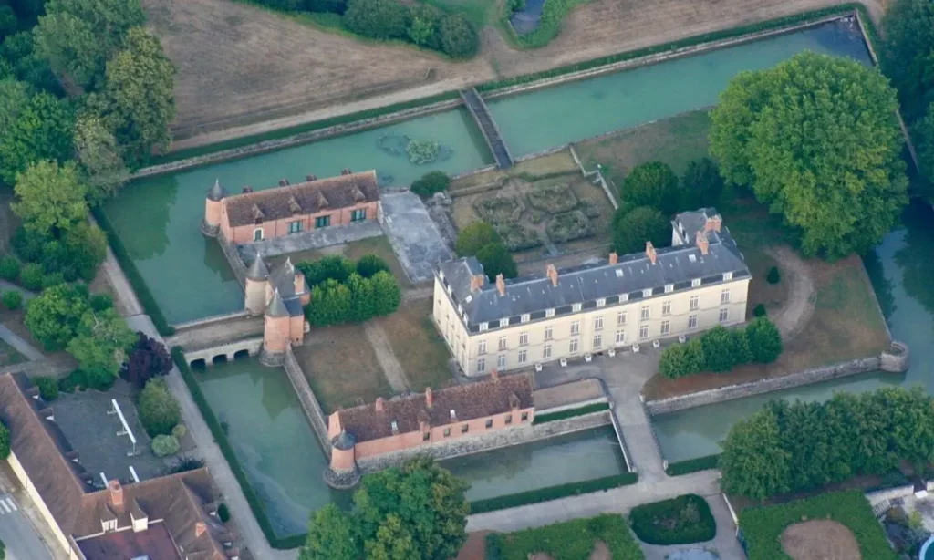 An aerial view of a historic chateau surrounded by water in the Seine Valley.