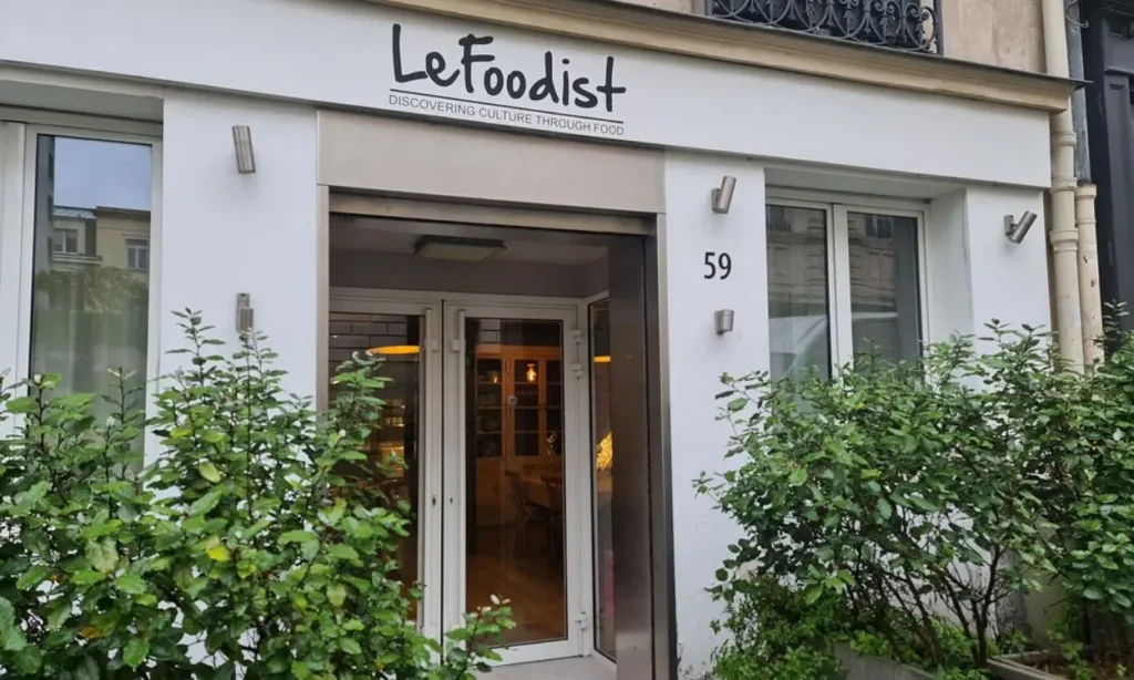 The entrance to Le Foodist cooking school in Paris with greenery around the doorway.