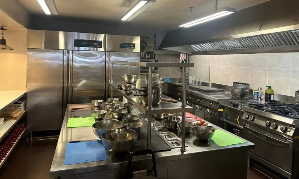 A professional kitchen with stainless steel equipment and ingredients prepared for a cooking class at Le Foodist.