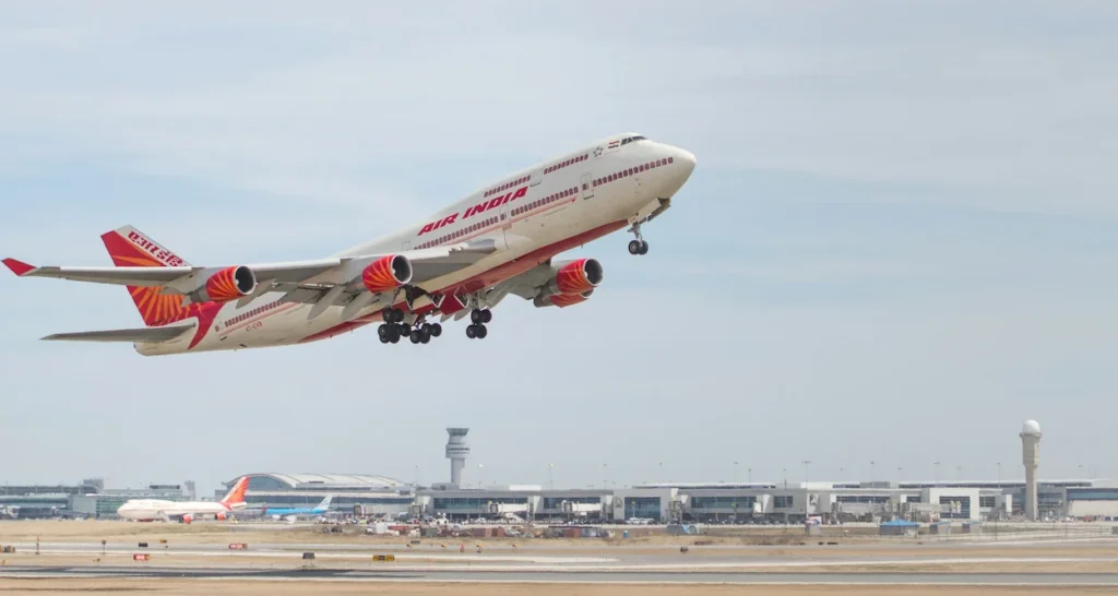An Air India Boeing 747 airplane taking off into the sky above an airport terminal