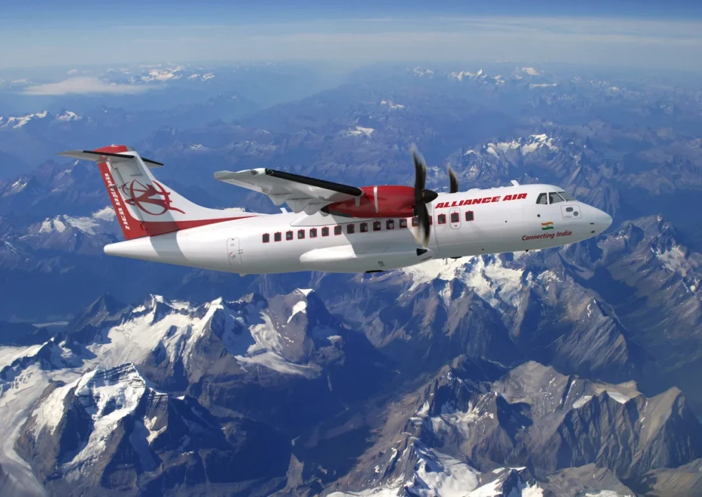 An Alliance Air turboprop passenger airplane flying high above snow-covered mountain peaks