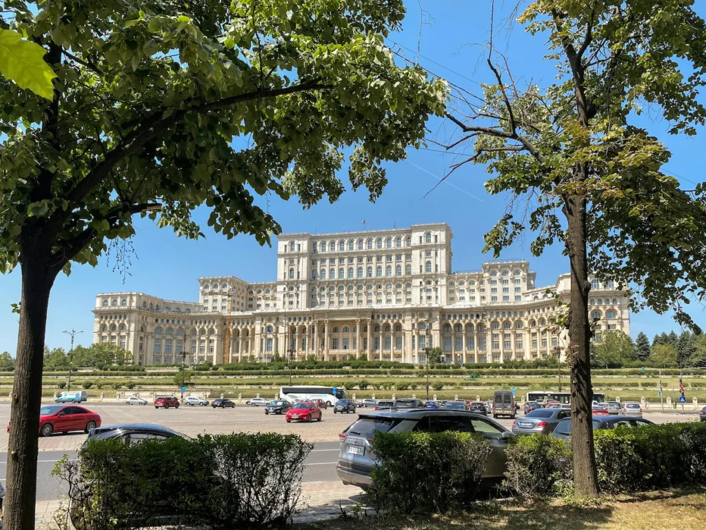 The monumental Palace of the Parliament building in Bucharest framed by green trees