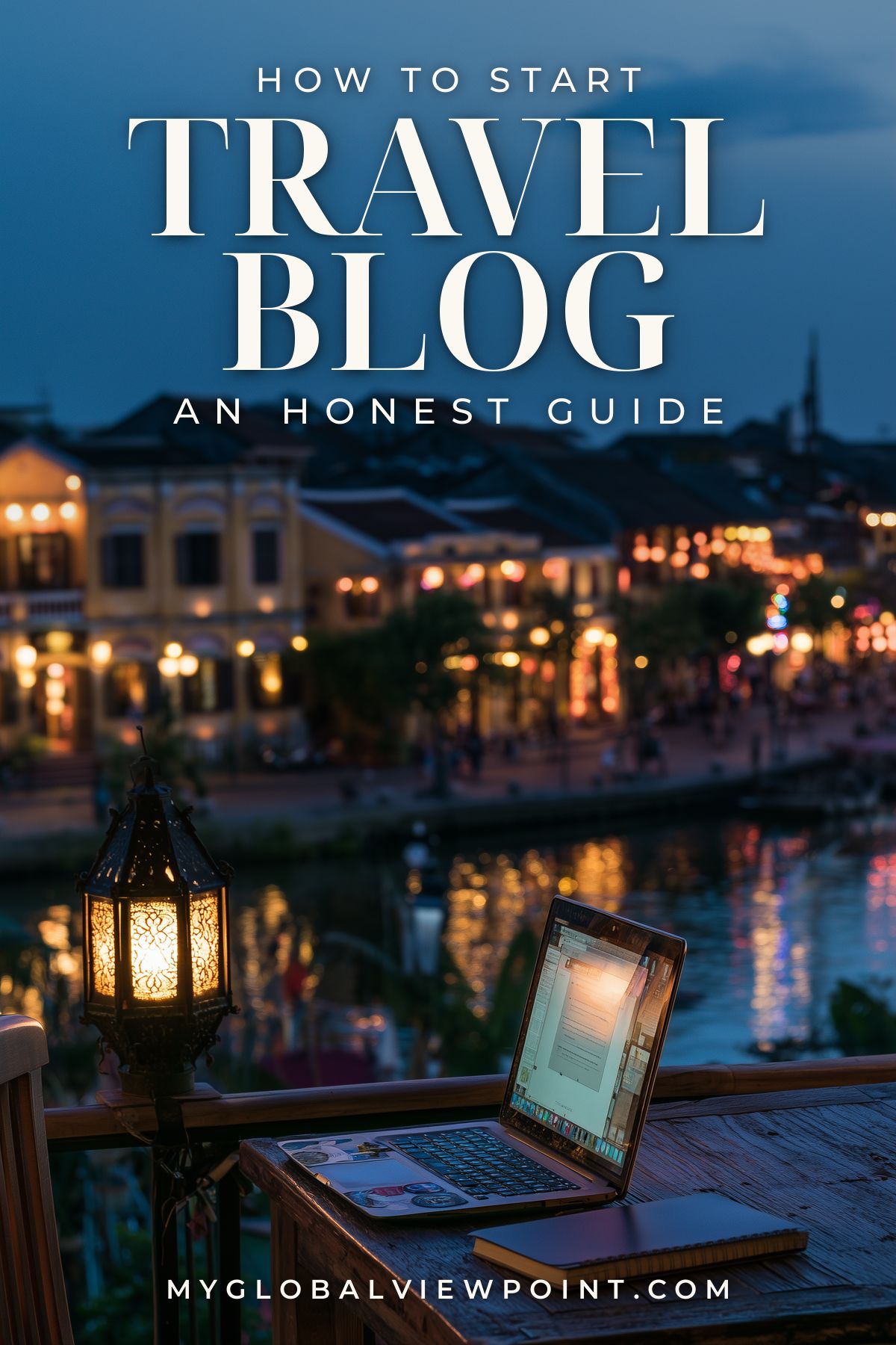 Starting a travel blog guide pin with a laptop and lantern overlooking a riverside town at dusk.